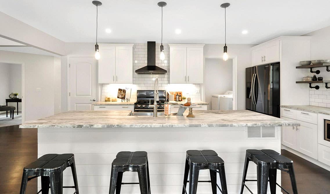 Summit Shaker White cabinets with large island, marble countertop, pendent lights, black stools 