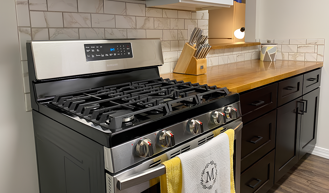 shaker espresso kitchen cabinets paired with wooden countertop and gas stove