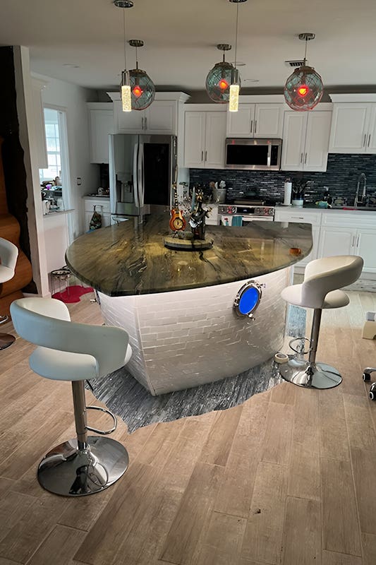 Ship Shaped kitchen Island paired with white stools 