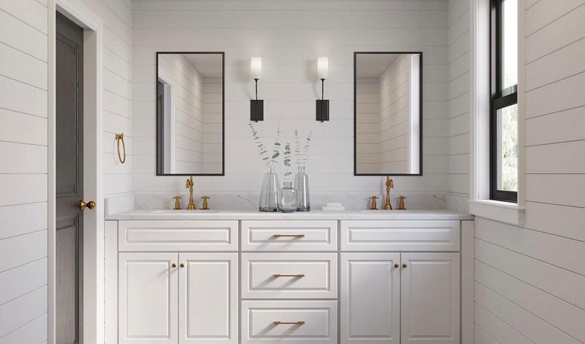 Bathroom design features shiplap paneling on walls, white vanity with marble countertops