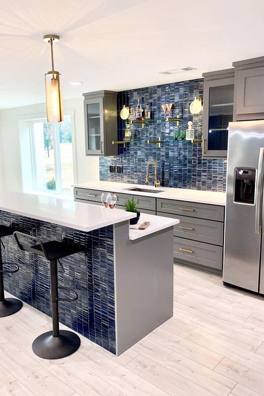 Stylish Kitchen with gray cabinets and blue subway tile backsplash, pendent lights above island 