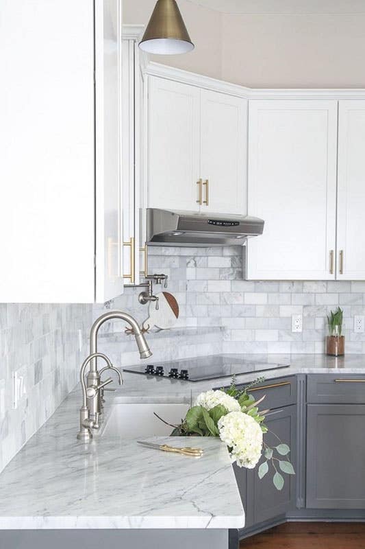 White and gray cabinets with marble countertop, sink, and gold pulls 