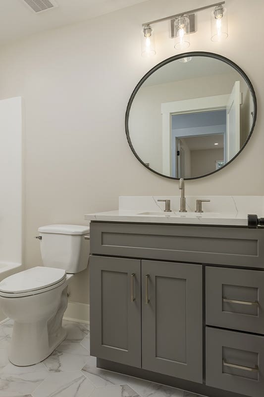 Sleek and Sophisticated Bathroom Design with gray vanity and round mirror