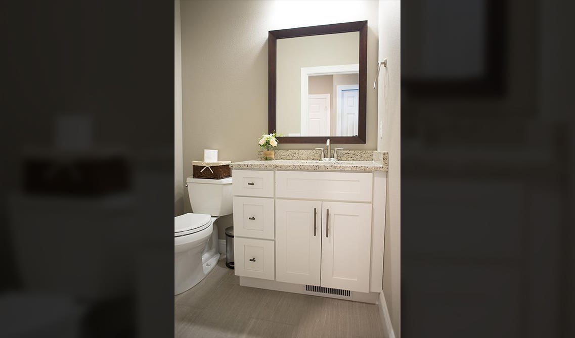 bathroom cabinets with silver hardware and large mirror