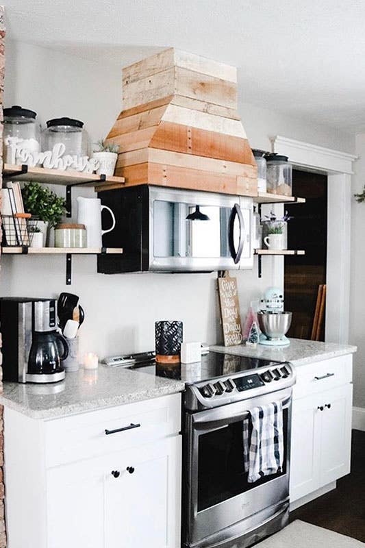 Small kitchen with white cabinets, open shelves, electric stove and range hood 