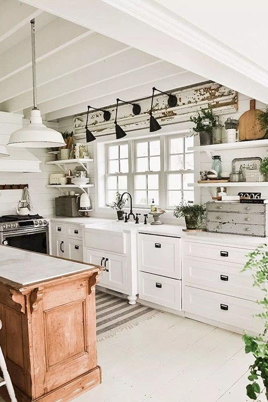 Small rustic kitchen with shaker cabinets and open shelving, window above sink, and small wooden island