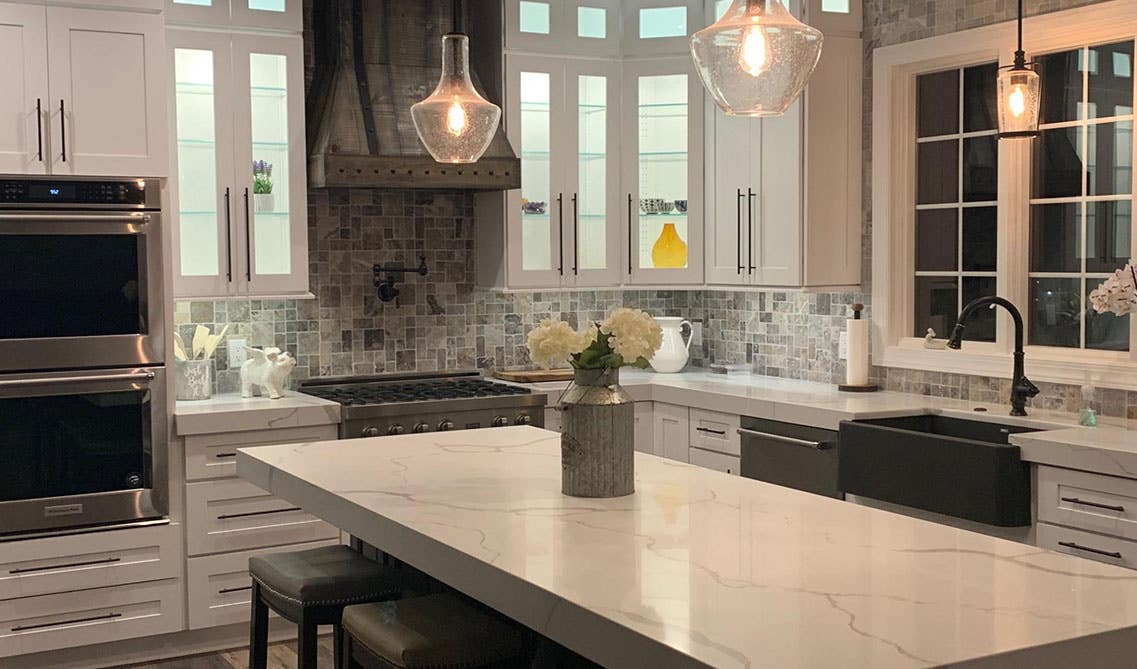 Elegant kitchen design with white cabinets, kitchen island, and square mosaic tile as backsplash 