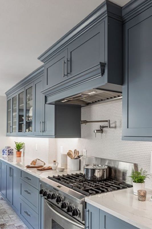 Modern kitchen with blue cabinets, white countertop, and stainless steel stove 