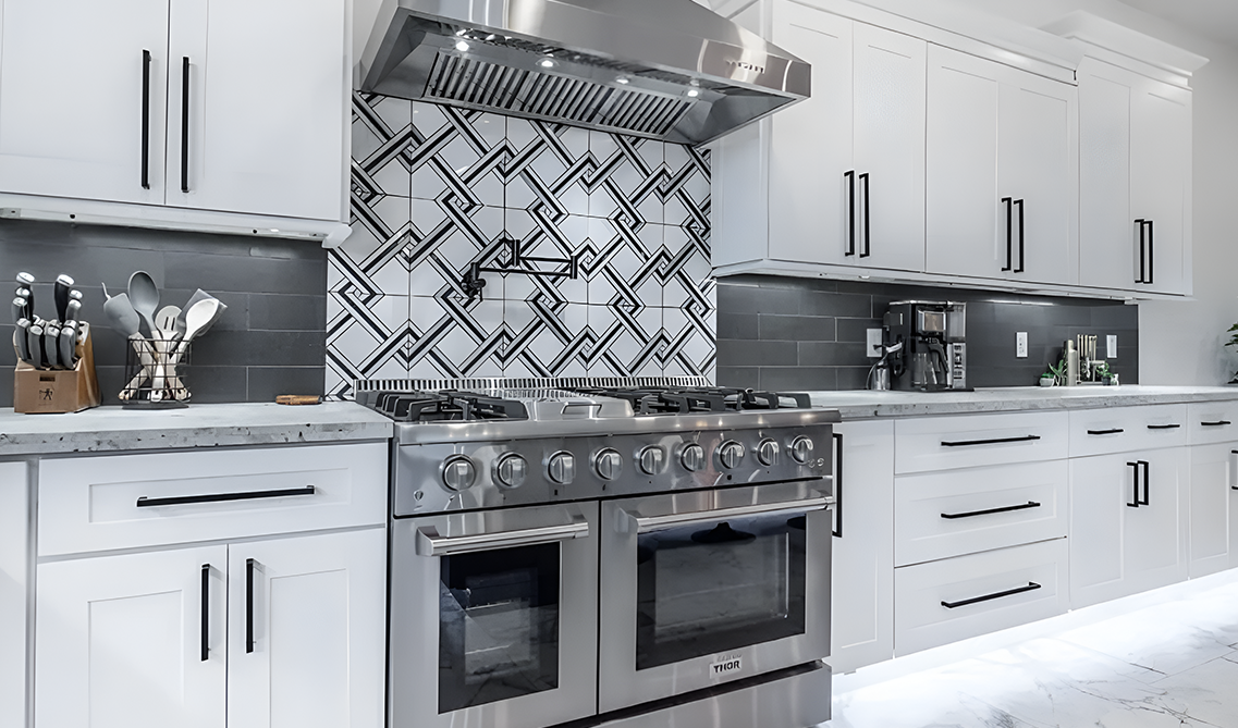 White and black kitchen paired with stainless steel range hood, matt black hardware, black tile backsplash and marble flooring 
