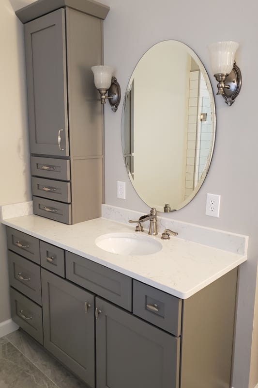 Bathroom design with Gray cabinets, vanity with marble countertop and statement mirror