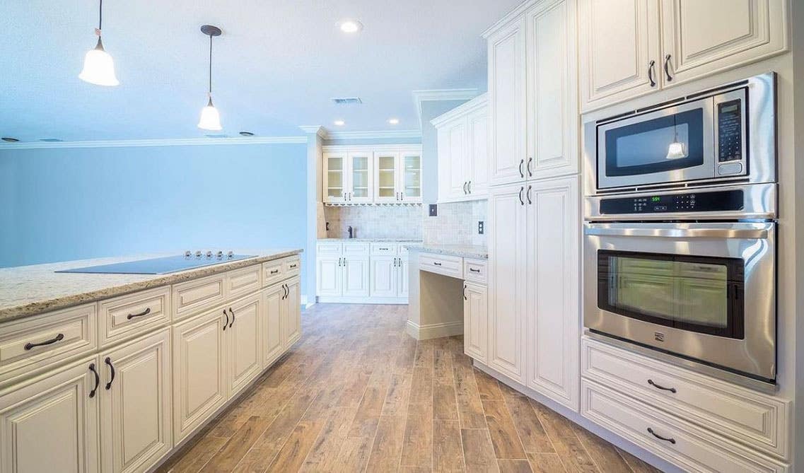 ceiling touch storage kitchen cabinets, stainless steel appliances an wooden flooring