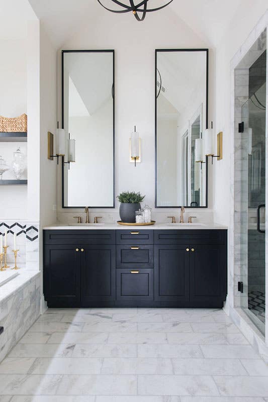 large modern bathroom with black shaker cabinets, large rectangular mirrors, white marble floors and brass hardware bathroom with black cabinets, large rectangular mirrors, white marble floors and brass hardware