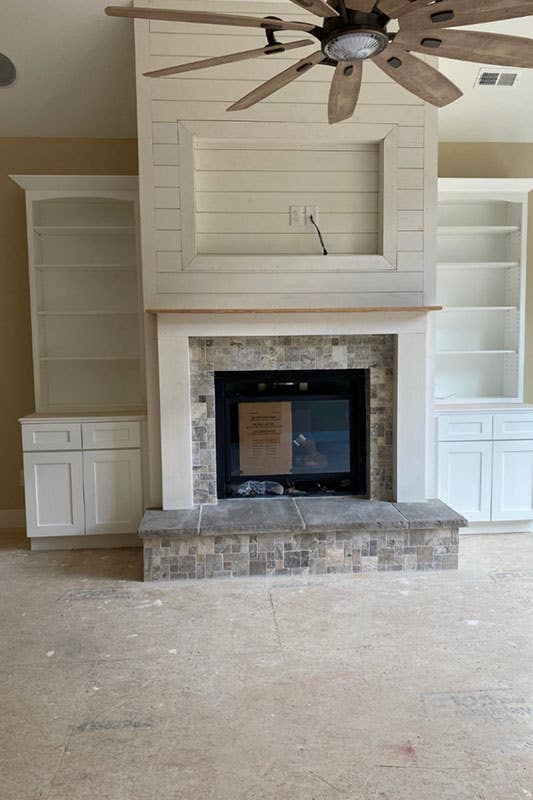 White storage cabinets around the electric fireplace and stone made hearth