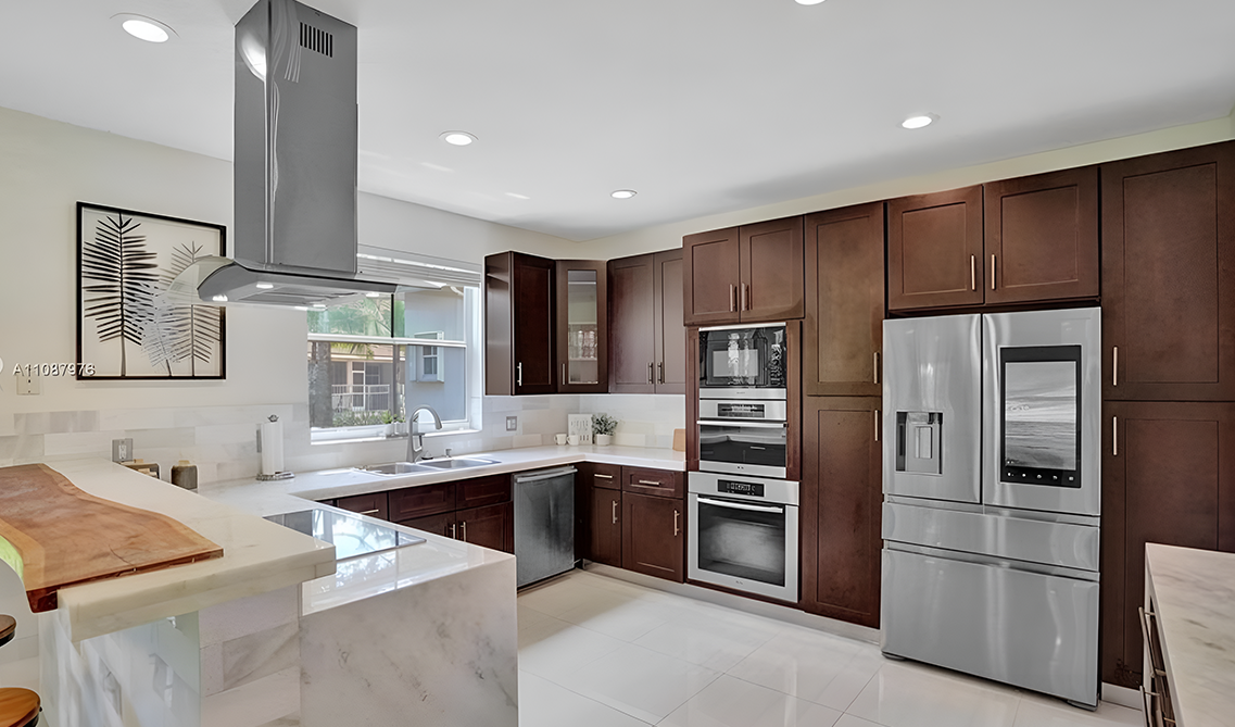 Modern kitchen design with brown cabinets paired with extended waterfall countertop and stainless steel appliances 