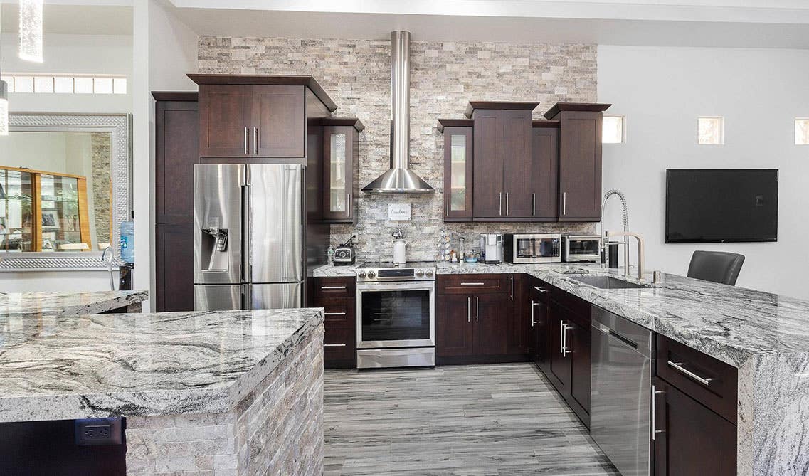 Stylish kitchen with brown cabinets and stainless steel appliances, marble countertop 