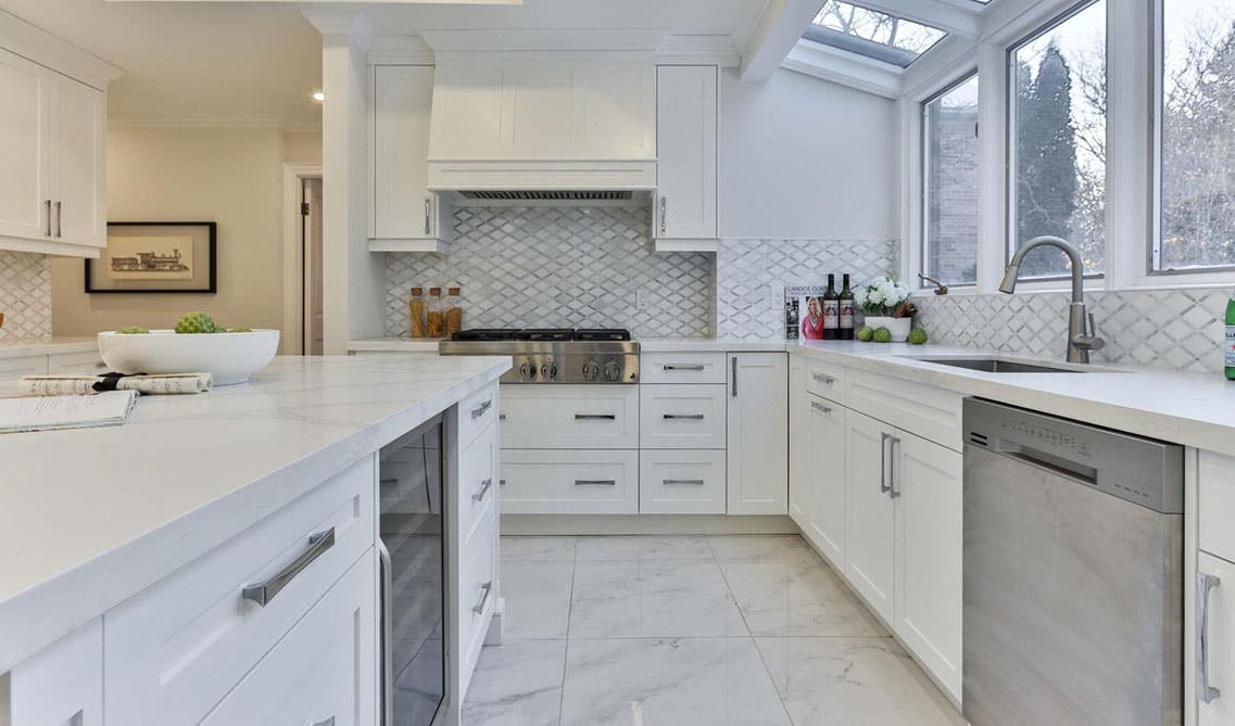 Stylish kitchen with white cabinets, large island, marble countertops and stainless steel appliances