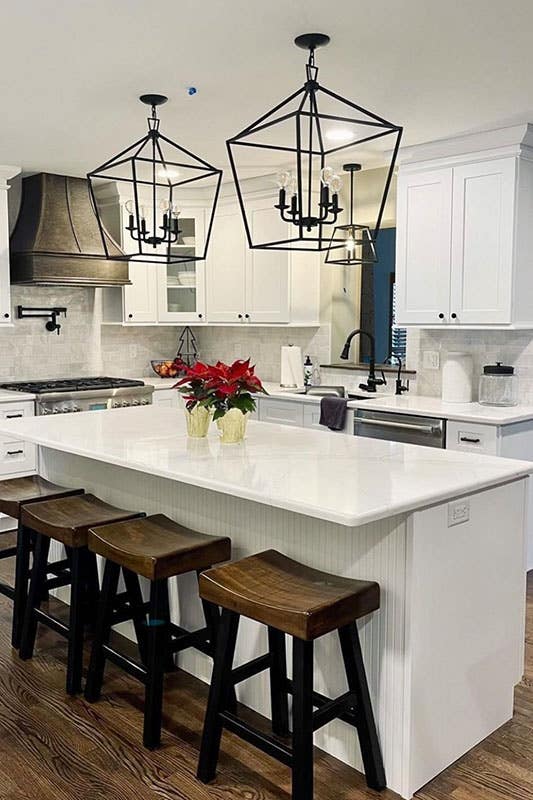 L shape white cabinets kitchen with small island and wooden stools