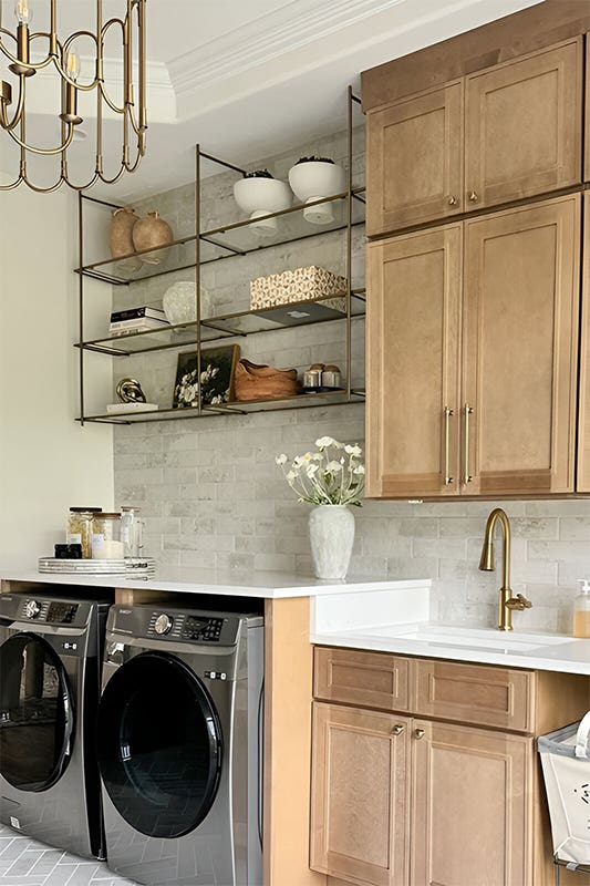 Laundry room design with woven baskets, textured wallpaper, washer, dryer and wooden ccabinets