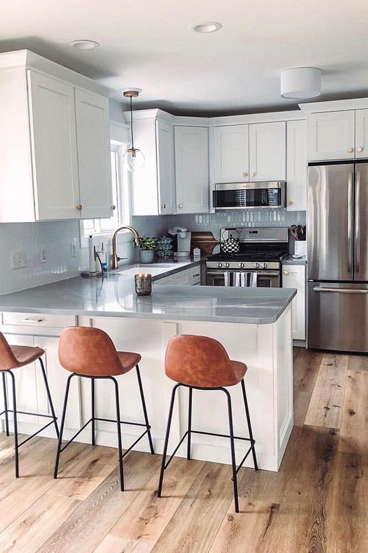 White kitchen with shaker cabinets, stainless steel appliances and extend island with chairs