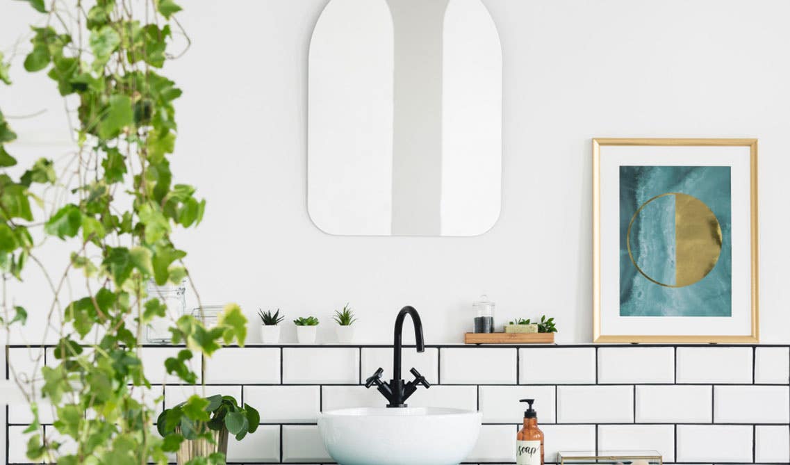 white small sink with black faucet and white subway tiles on wall