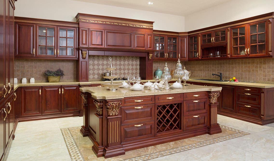 Traditional Kitchen style with Glass cabinets, Gold hardware, large island, cream marble countertops and marble tile flooring 