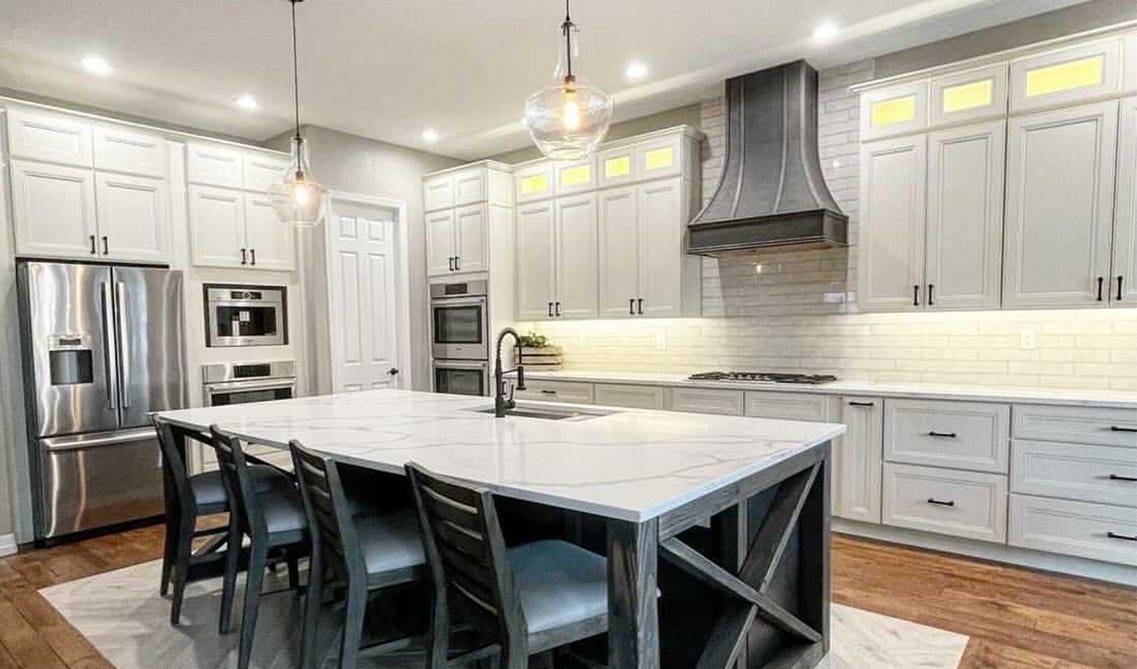 White traditional kitchen cabinets paired with gray range hood, stainless steel appliances and spc flooring