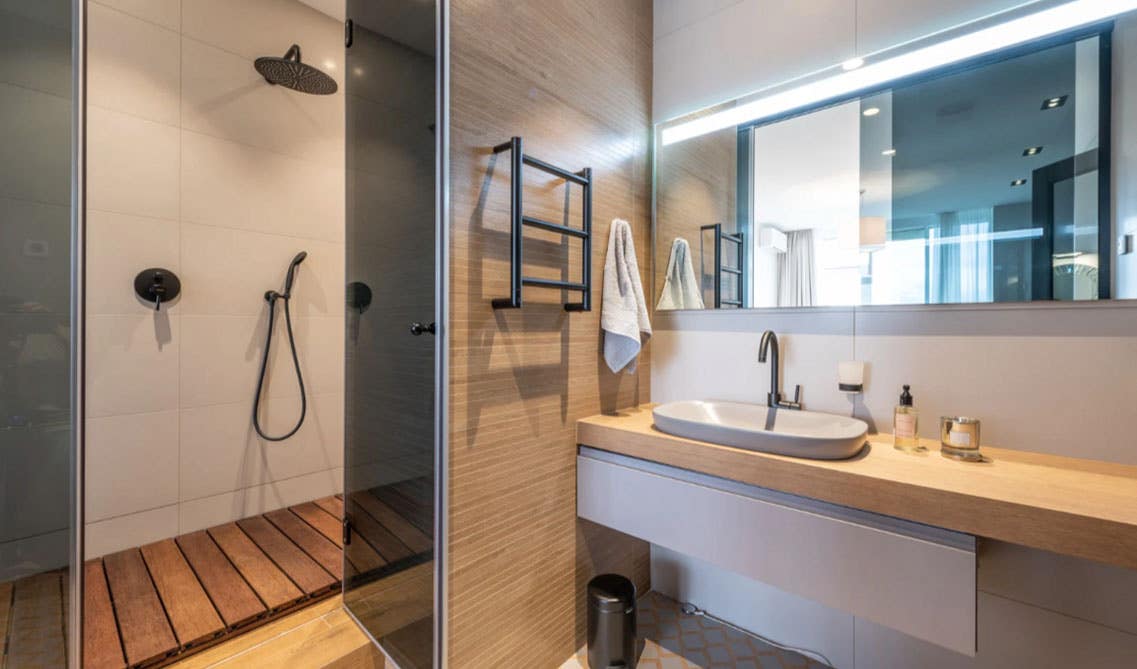 Simple bathroom design features transitional vanities and wood countertops, separate shower area 