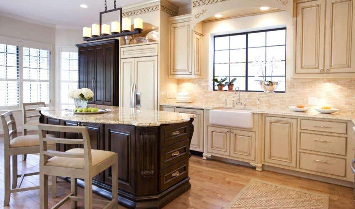 Tuscan kitchen design paired with cream wall cabinets and dark cabinet island