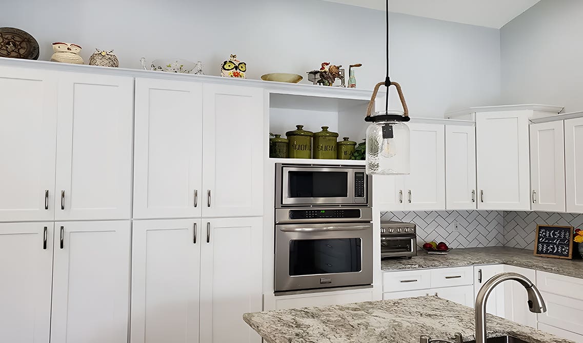 Open concept kitchen paired with white microwave cabinets, silver pulls, and functional island 