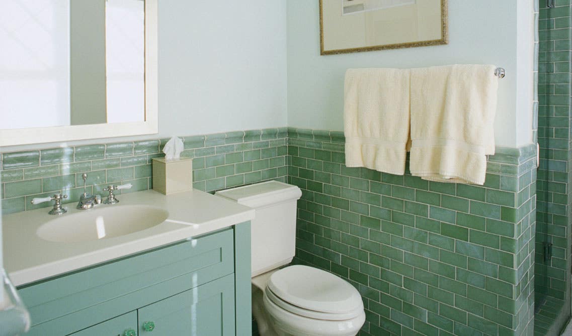 white bathroom with green vanity and green subway tile