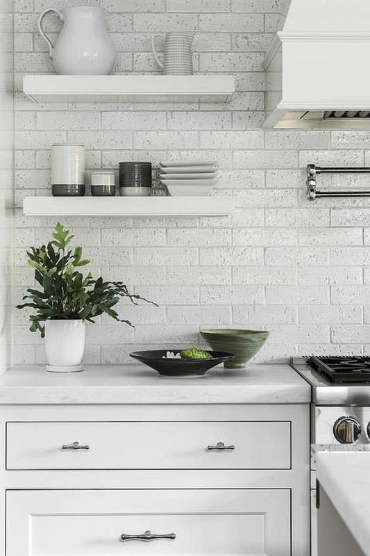 White Brick Backsplash with Floating Shelves and bright white cabinets