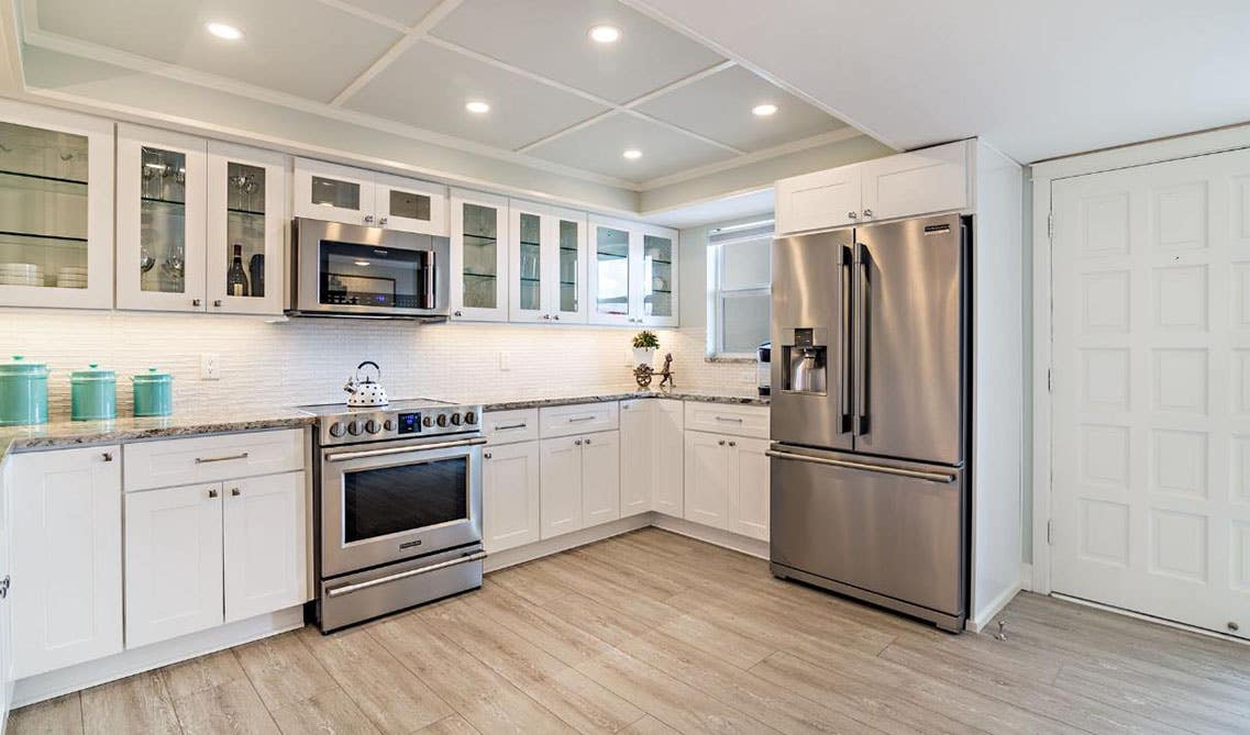 Kitchen design with white cabinets, quartz countertop, stainless steel appliances and wooden flooring