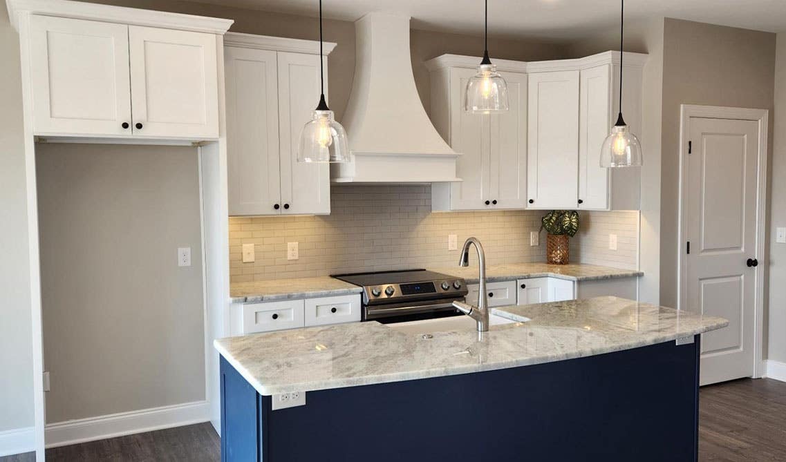 White Cabinets with Navy Blue Shaker Island Cabinets and pendent lights over island 