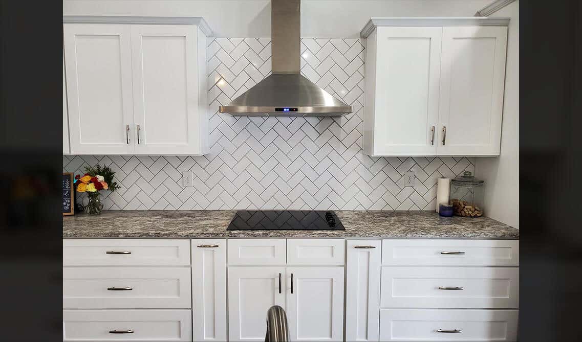 white kitchen cabinets with silver hardware, countertop, range hood, electric stove