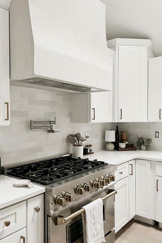 Kitchen With White Shaker cabinets with gold hardware, white countertop, subway tile backsplash