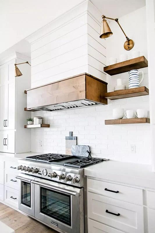 rustic kitchen with white cabinets, subway tiles, wood open shelves and gas stove