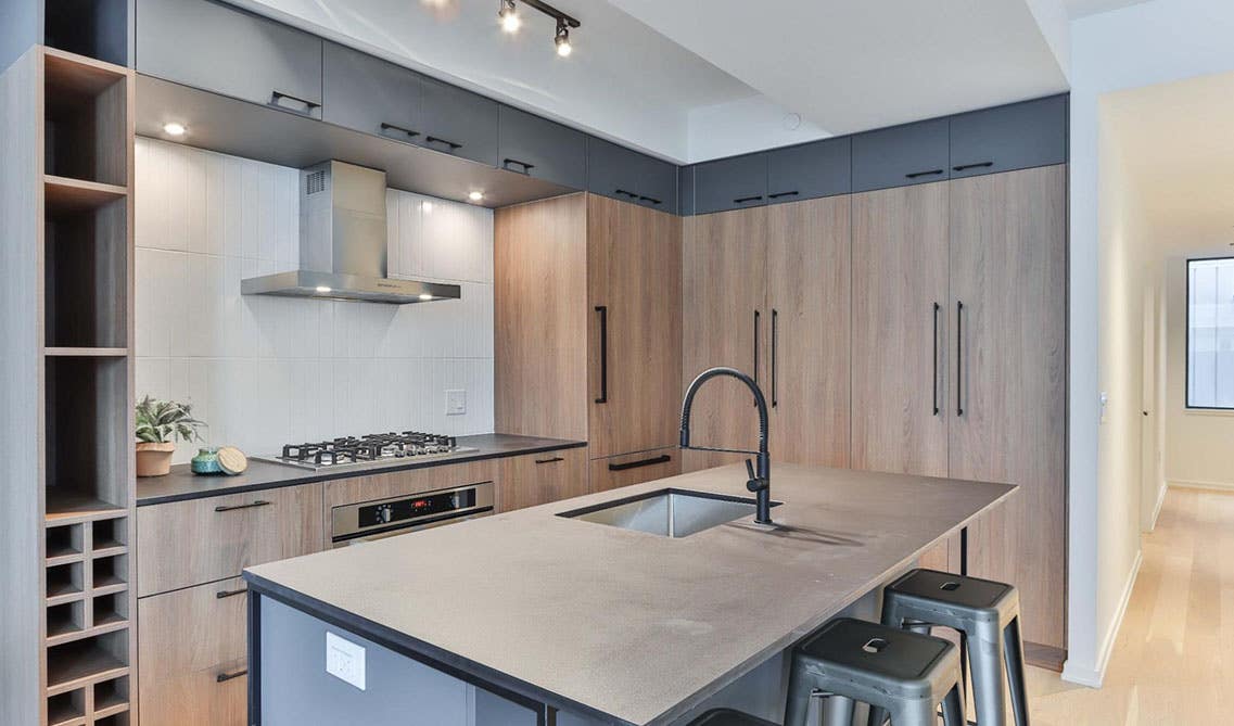 Modern kitchen with white oak cabinets, black accent, island with sink, and subway tile backsplash 