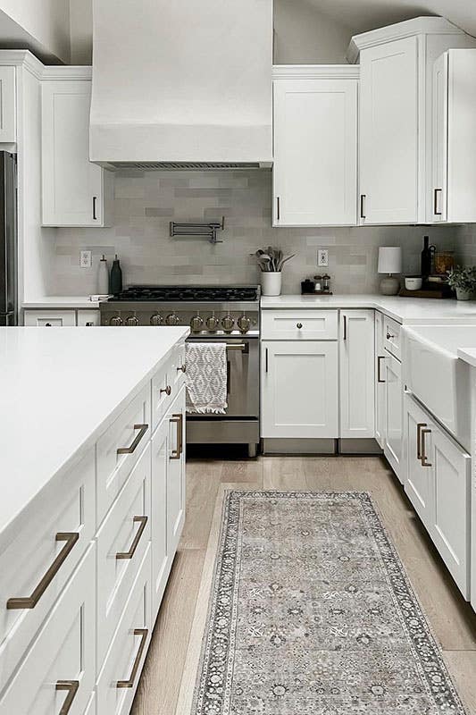 white cabinets with metal hardware and wooden range hood