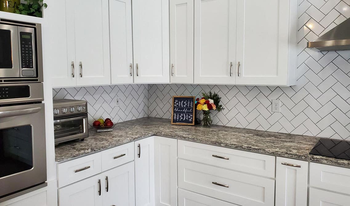 White kitchen cabinets with silver pulls with subway white tiles, Marble Countertops