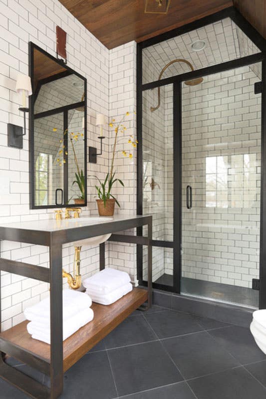 modern bathroom with white subway tile backsplash, black framed shower, grey floor tile