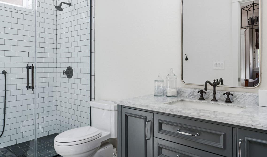 white bathroom with subway tiles, gray vanity with marble countertop, and black matt hardware