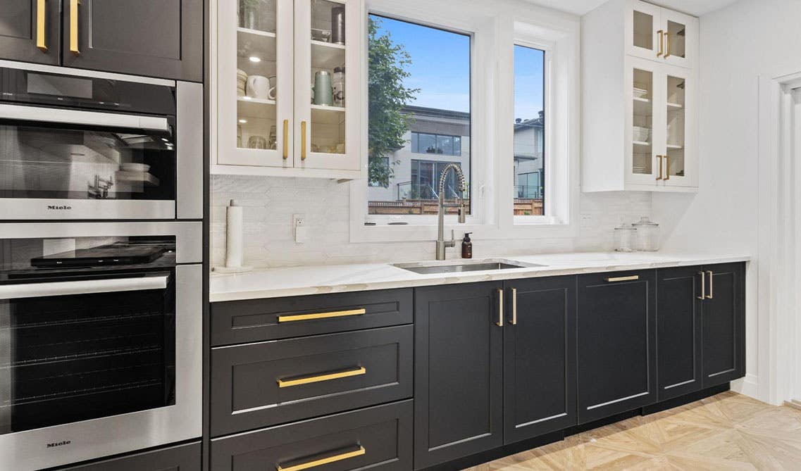 Farmhouse kitchen features White wall cabinets With a Black Island and tile backsplashes