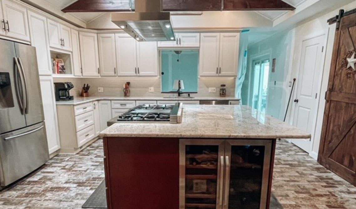 Farmhouse kitchen features White cabinets with a Cherry Island and tile flooring