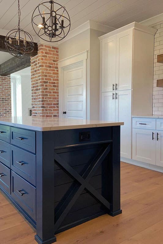 Farmhouse kitchen features White cabinets With a Navy Blue Island and spc flooring