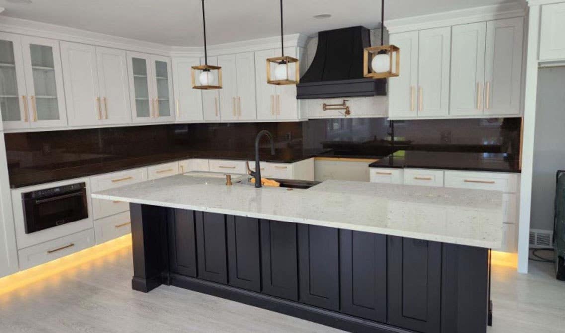 Bold kitchen design with white cabinets with black backsplash and gold hardware 