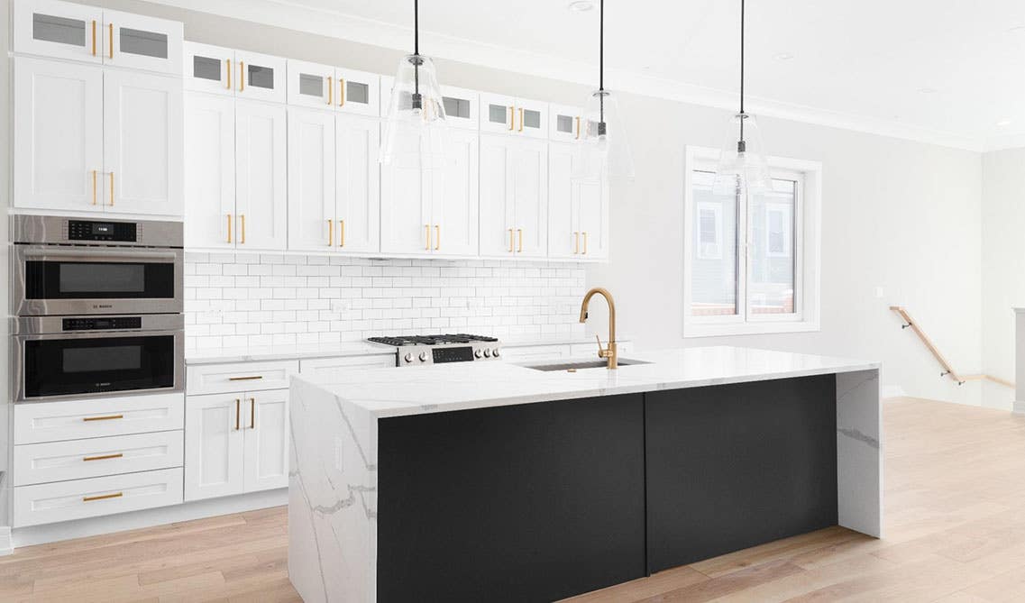 White and black kitchen design with shaker cabinets, large functional island with undermount sink, marble waterfall countertop 