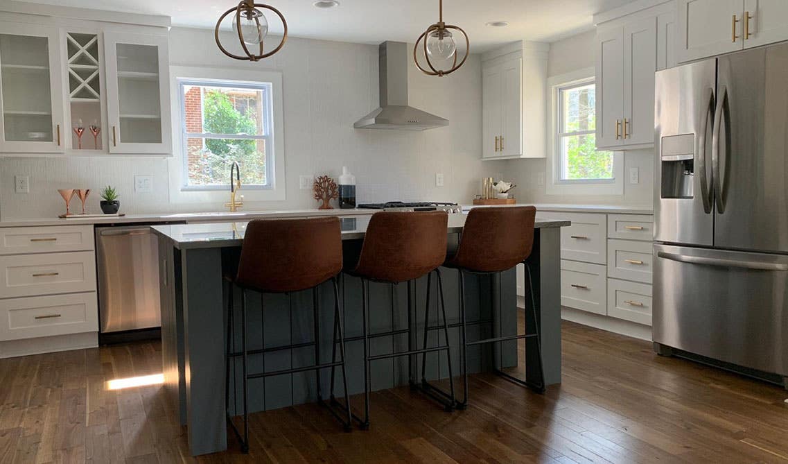 White and grey cabinets kitchen with gold hardware, pendent lights, small island with chairs