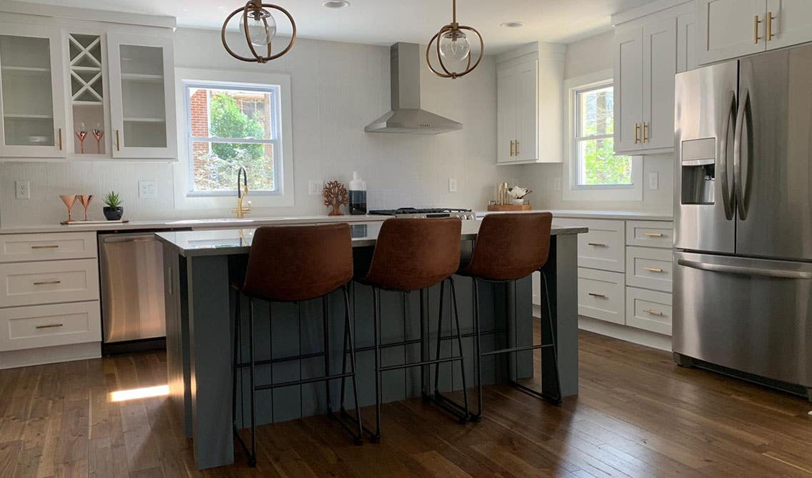 White and grey cabinets kitchen with gold hardware, pendent lights, small island with chairs