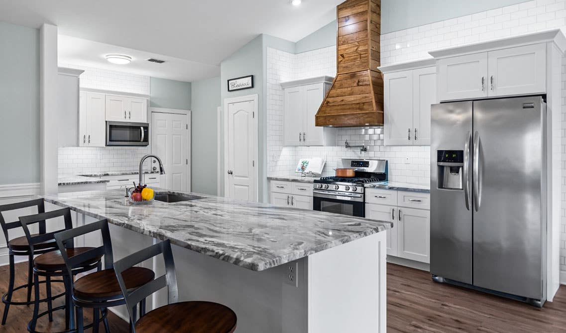 White kitchen with shaker cabinets with quartz countertop and stainless steel appliances 