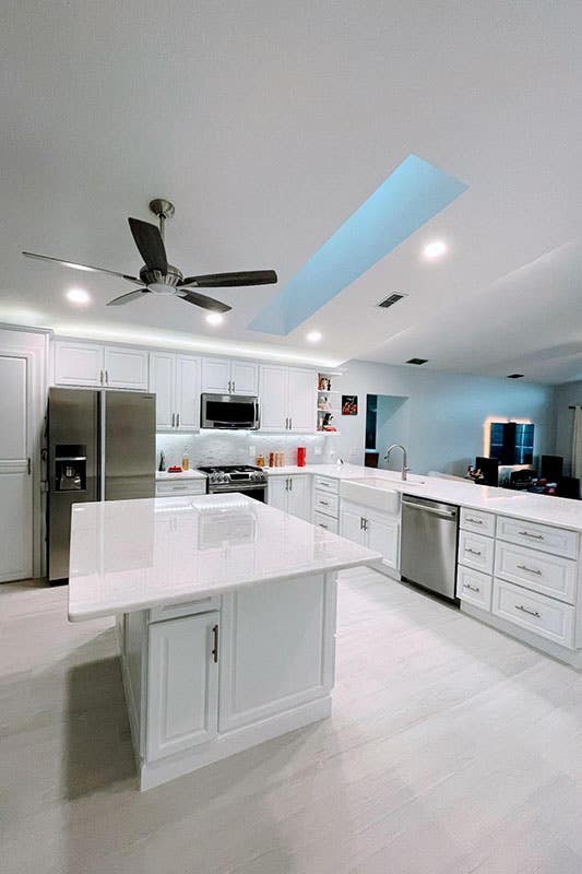 white kitchen design with key largo cabinets, white island, stainless steel hardware, ceiling Fan